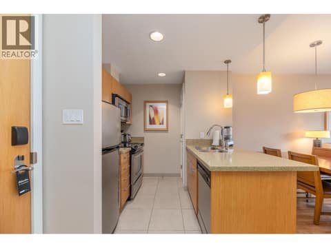 Efficient galley kitchen with peninsula seating and pendant lighting. at 15 PARK Place Unit# 209, Osoyoos