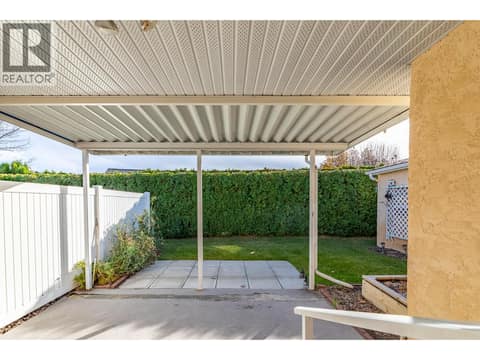 Covered rear patio looks toward the lawn, hedge and paved sitting area. at 145 REDWING Place Unit# 7, Oliver