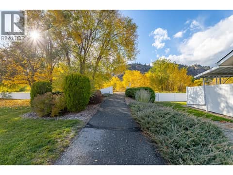 Landscaped pedestrian walkway is framed by mature trees and shrubs. at 145 REDWING Place Unit# 7, Oliver
